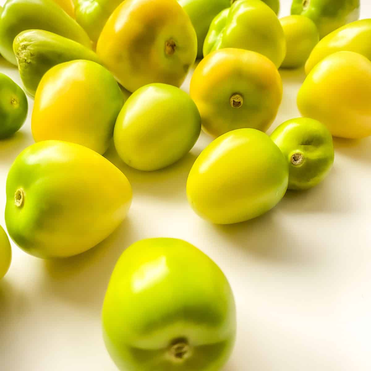 An image of yellow tomatillos on a white countertop.