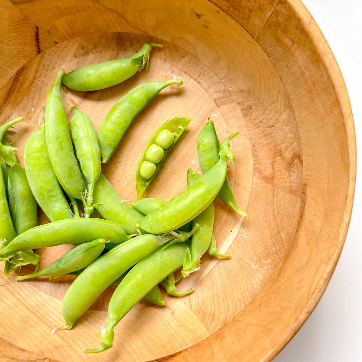 A bowl filled with shelling peas.
