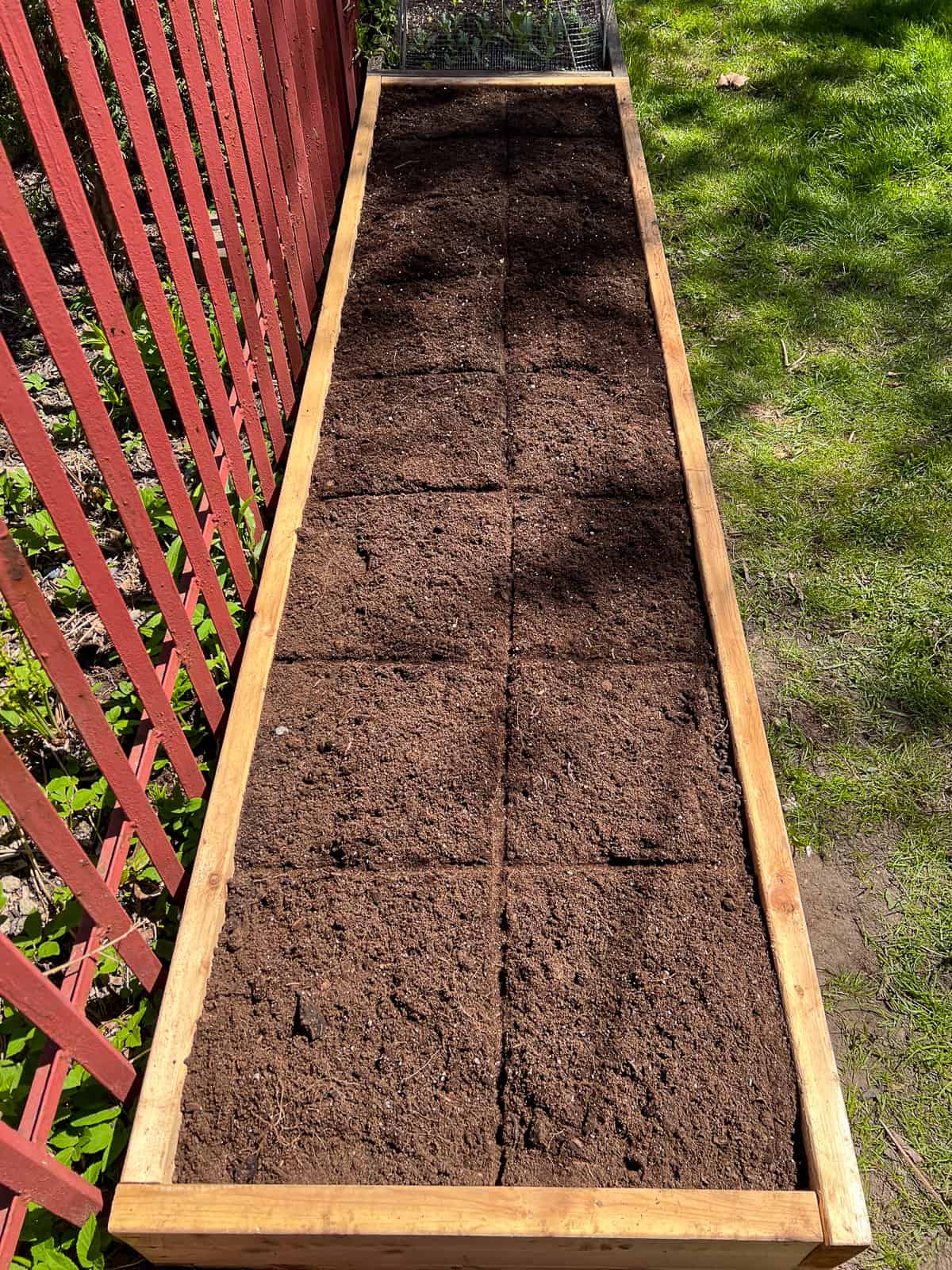 An image of a raised bed filled with soil and divided into square foot plots.
