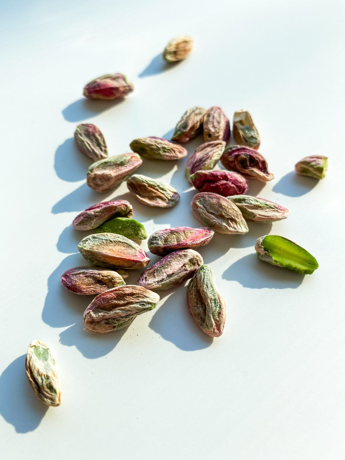 A close up image of shelled pistachios on a white counter top.