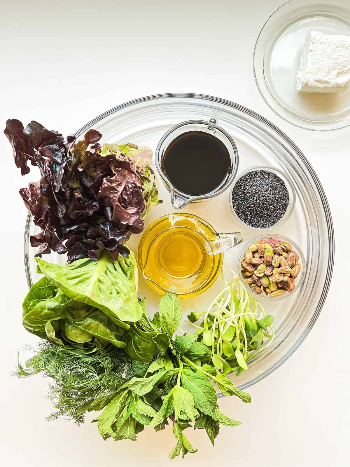 An image of a glass bowl containing the ingredients needed to make a spring salad.