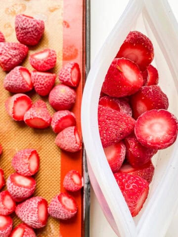 An image of frozen strawberries on a tray, that are going to be packed into silicone pouches to put into the freezer.