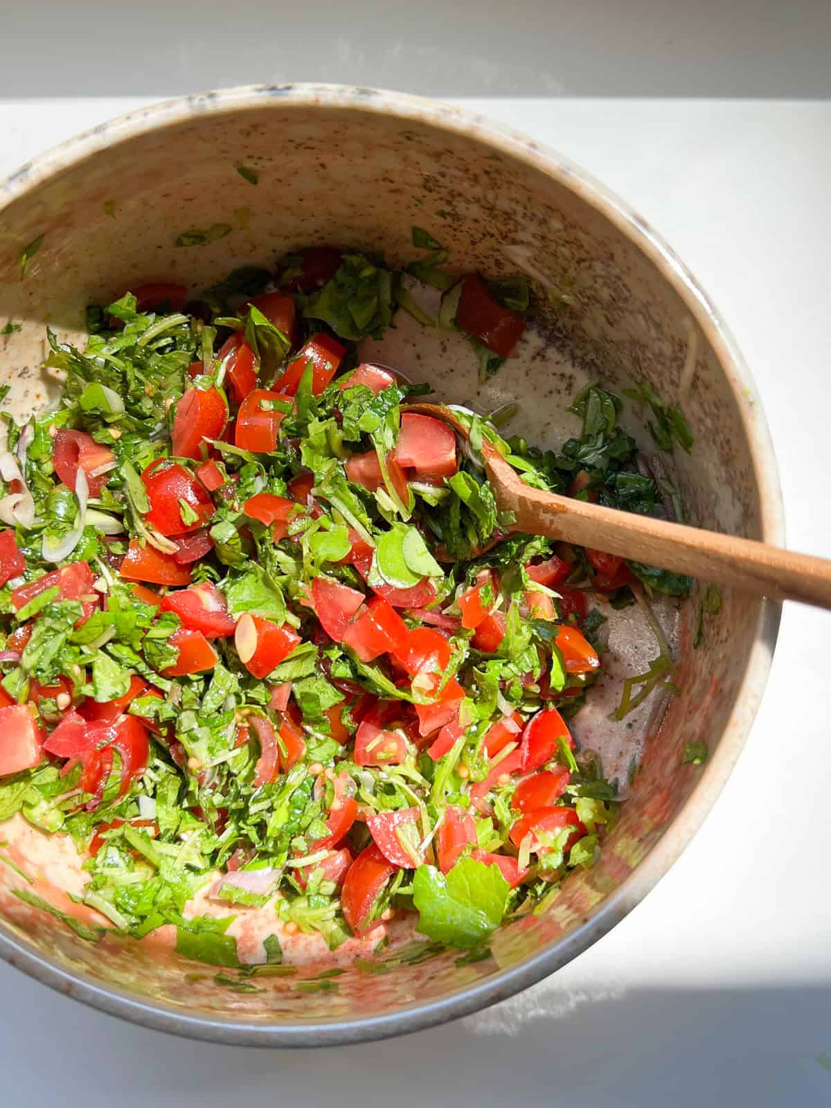 An image of radish leaf salsa in a ceramic bowl, sitting on a white counter.