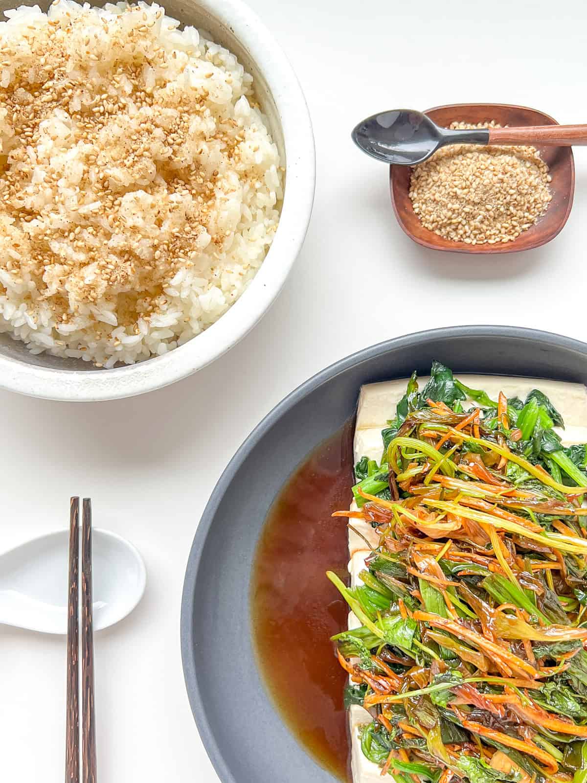 A meal laid out on a white countertop with Steamed Tofu with Ginger and Fragrant Greens as the centrepiece.